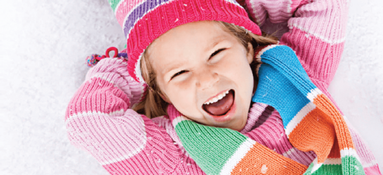 An image of a smiling girl in the snow.