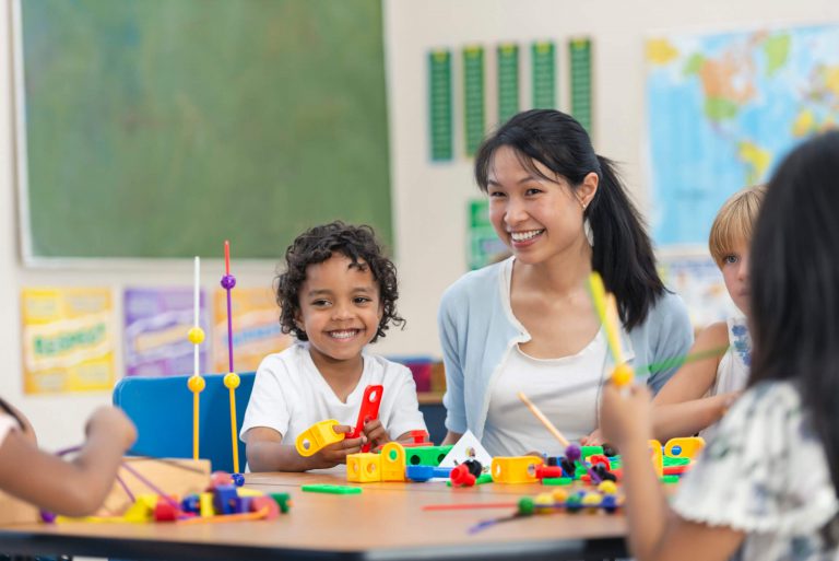 A group of students at a table playing with colorful building blocks.