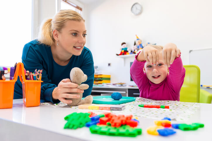 A mother and daughter practicing fine motor skills with small colorful blocks.