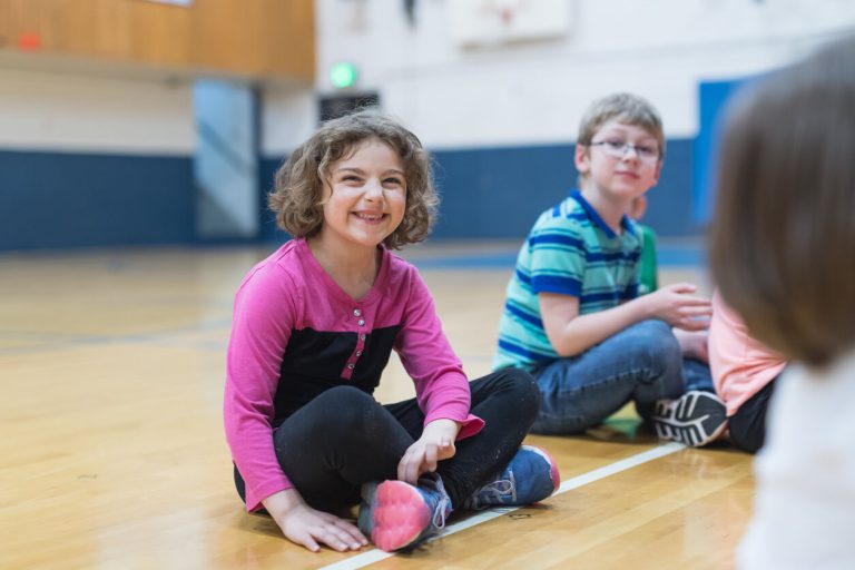 adapted-physical-education A group of students seated on a gymnasium floor.