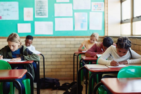Students seated at their desks and taking a test in a classroom.