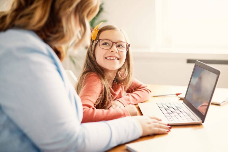 A mother and a daughter in front of a laptop.
