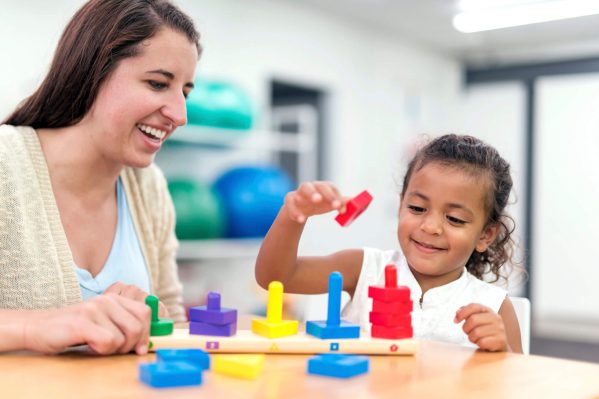 A girl and her teacher completing a color sorting activity.