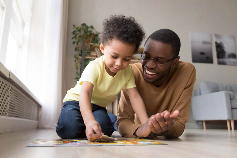 A father cheering on his young son while he completes a puzzle.