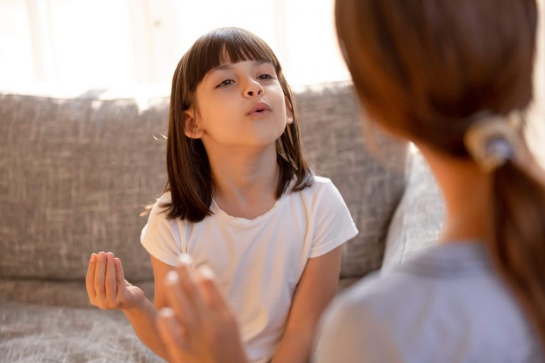 A girl practicing pronunciation exercises with a speech therapist.