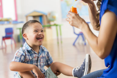 A happy young child excited to see the bubbles their teacher is blowing.